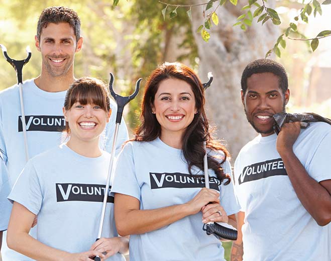 Volunteers holding tools during outdoor cleanup