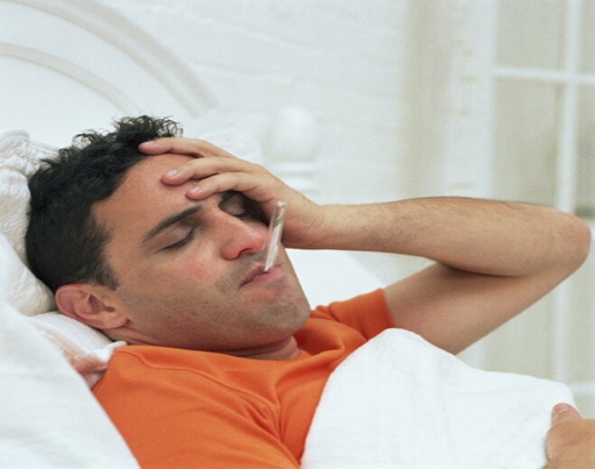Person resting in bed with thermometer