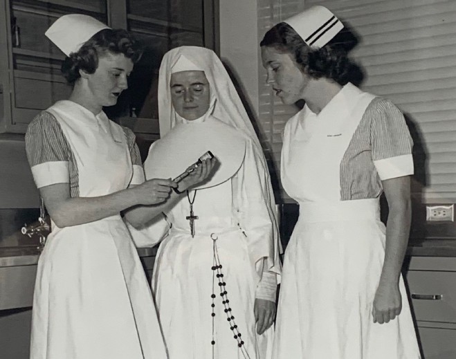 Three nurses in traditional uniforms conversing