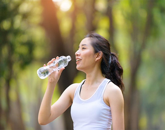 Person drinking water outdoors in sunlight