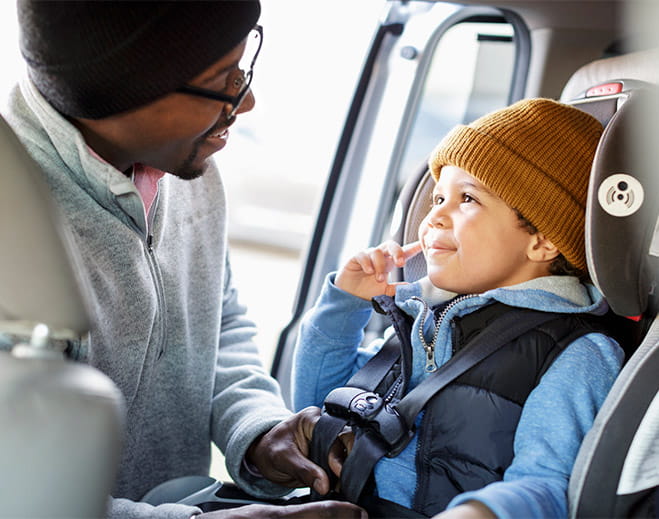Adult securing child in car seat