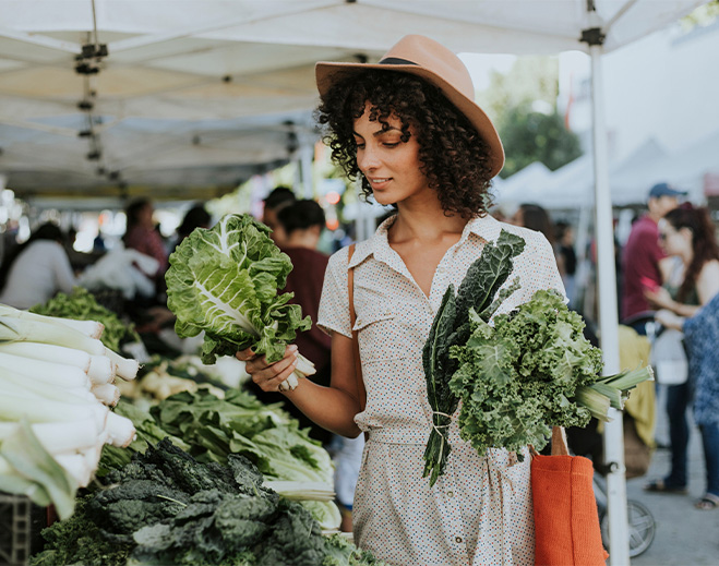 Person selecting leafy greens at market